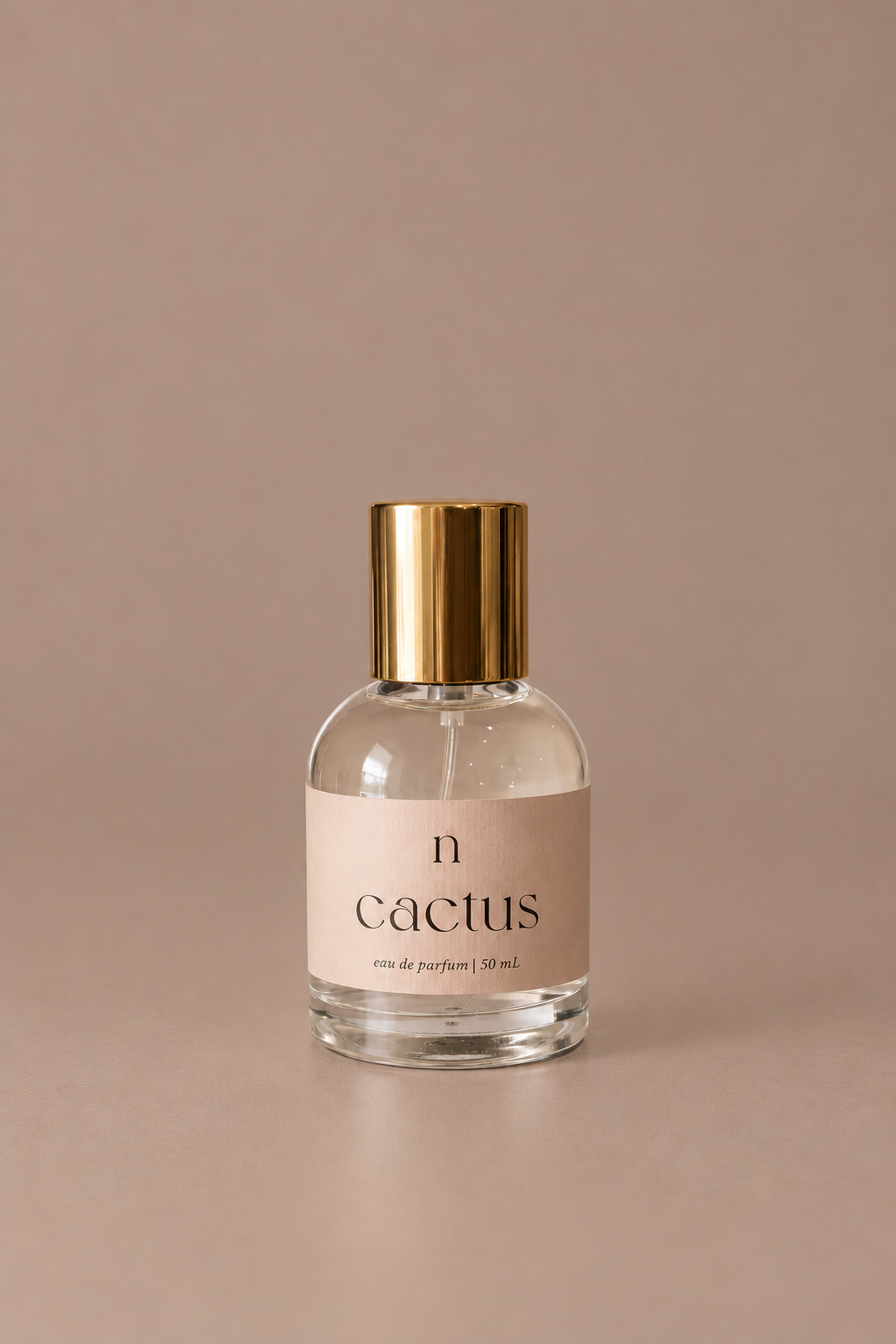 Naked Goat Cactus 50 mL eau de parfum in a clear glass bottle with gold cap on a seamless mushroom studio background.