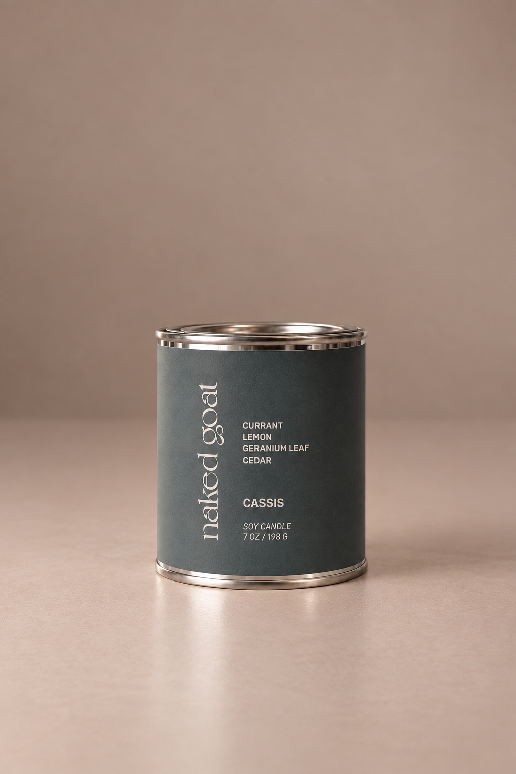 Naked Goat Cassis soy candle with currant, lemon, geranium leaf and cedar on a seamless mushroom studio background.