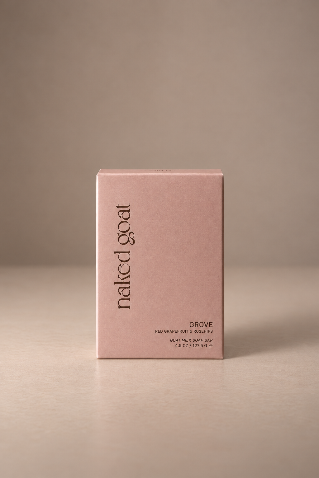 Naked Goat Grove red grapefruit and rosehips goat milk soap bar in blush packaging on a mushroom studio background.