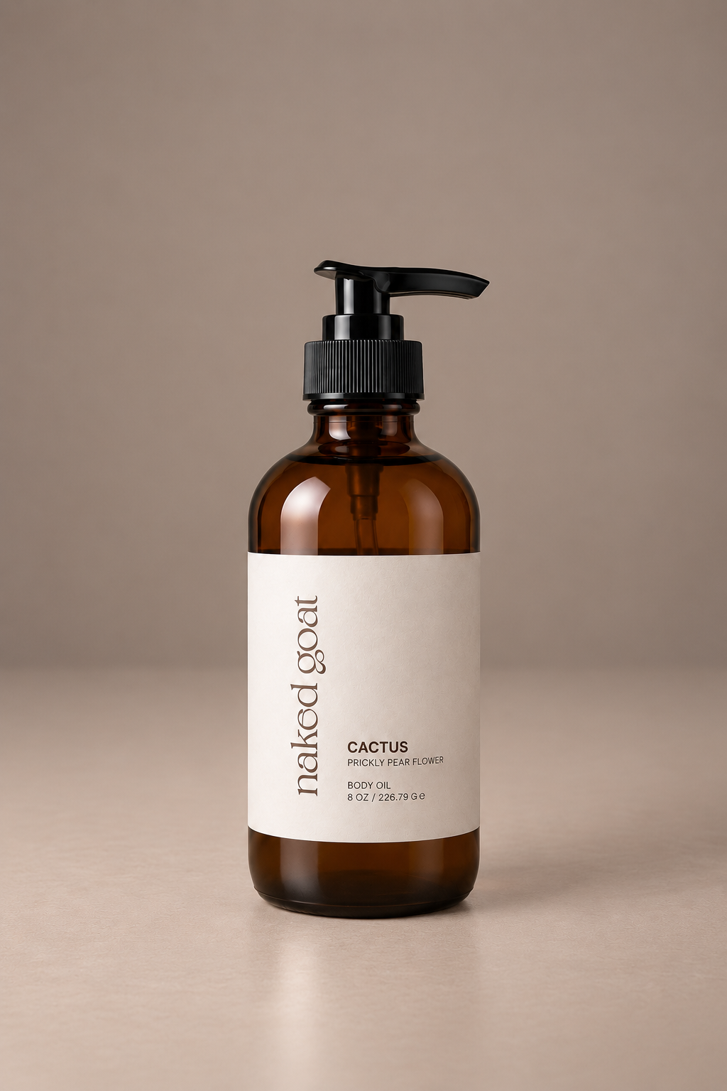 An amber glass pump bottle of Naked Goat Cactus body oil with a black pump and a minimalist label, set against a solid warm beige background.