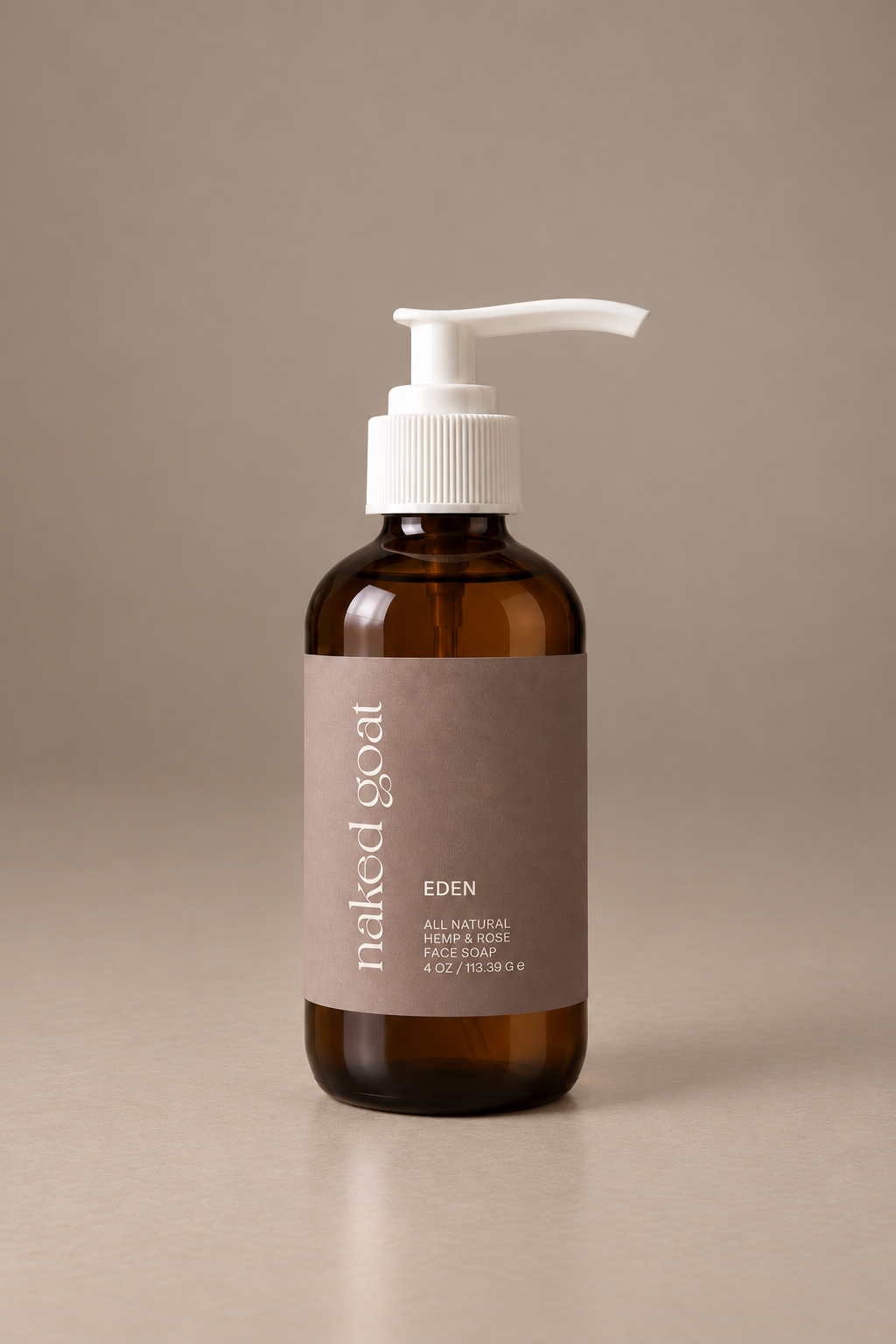 Naked Goat Eden hemp and rose face soap in an amber glass pump bottle on a seamless mushroom studio background.