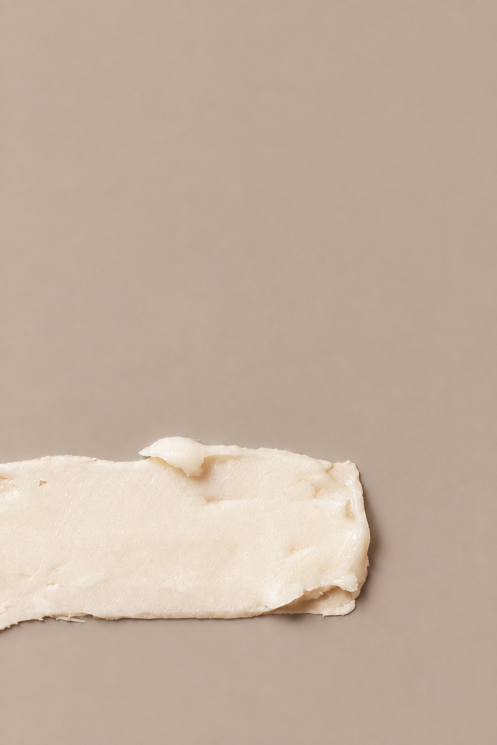 Mend peppermint lip conditioner creamy balm texture swatch on a seamless mushroom studio background.