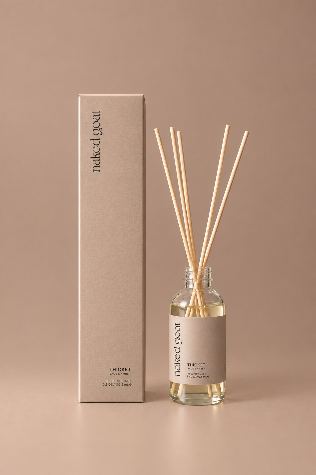 Naked Goat Thicket sage and amber reed diffuser with matching box on a seamless mushroom studio background.