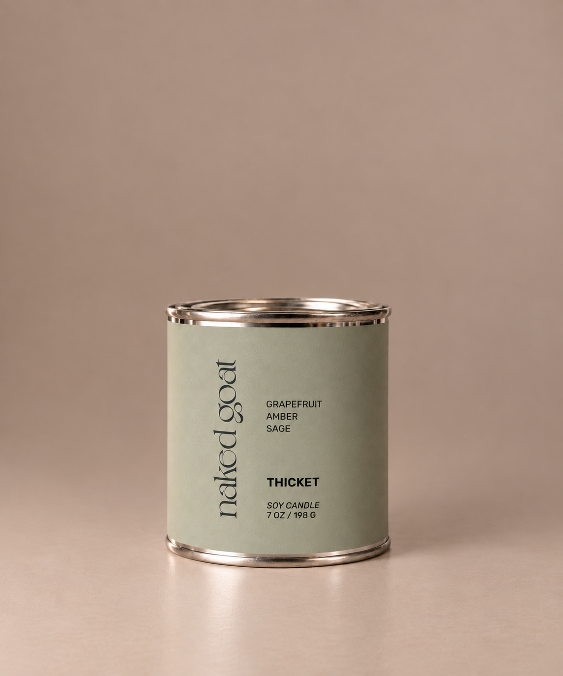 Naked Goat Thicket soy candle with grapefruit, amber and sage on a seamless mushroom studio background.